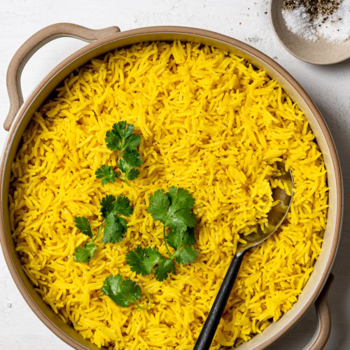 turmeric rice pilaf in serving bowl garnished with cilantro leaves