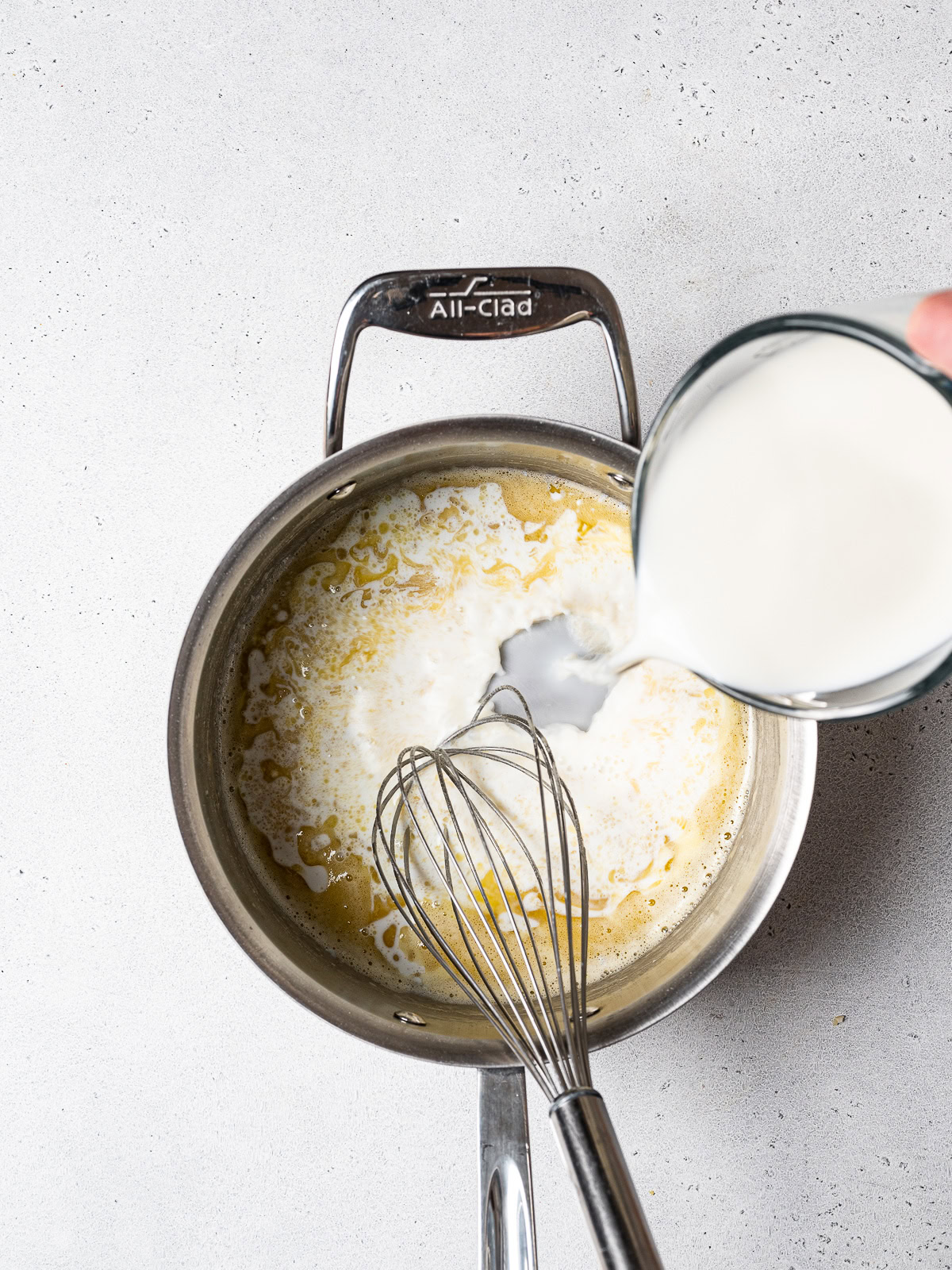 pouring milk into pan with roux