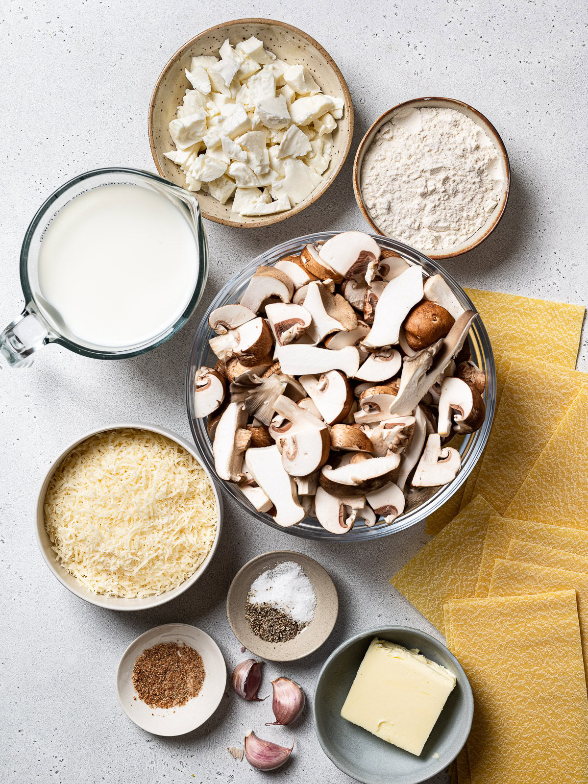 Ingredients to make mushroom lasagna sorted in separate bowls 