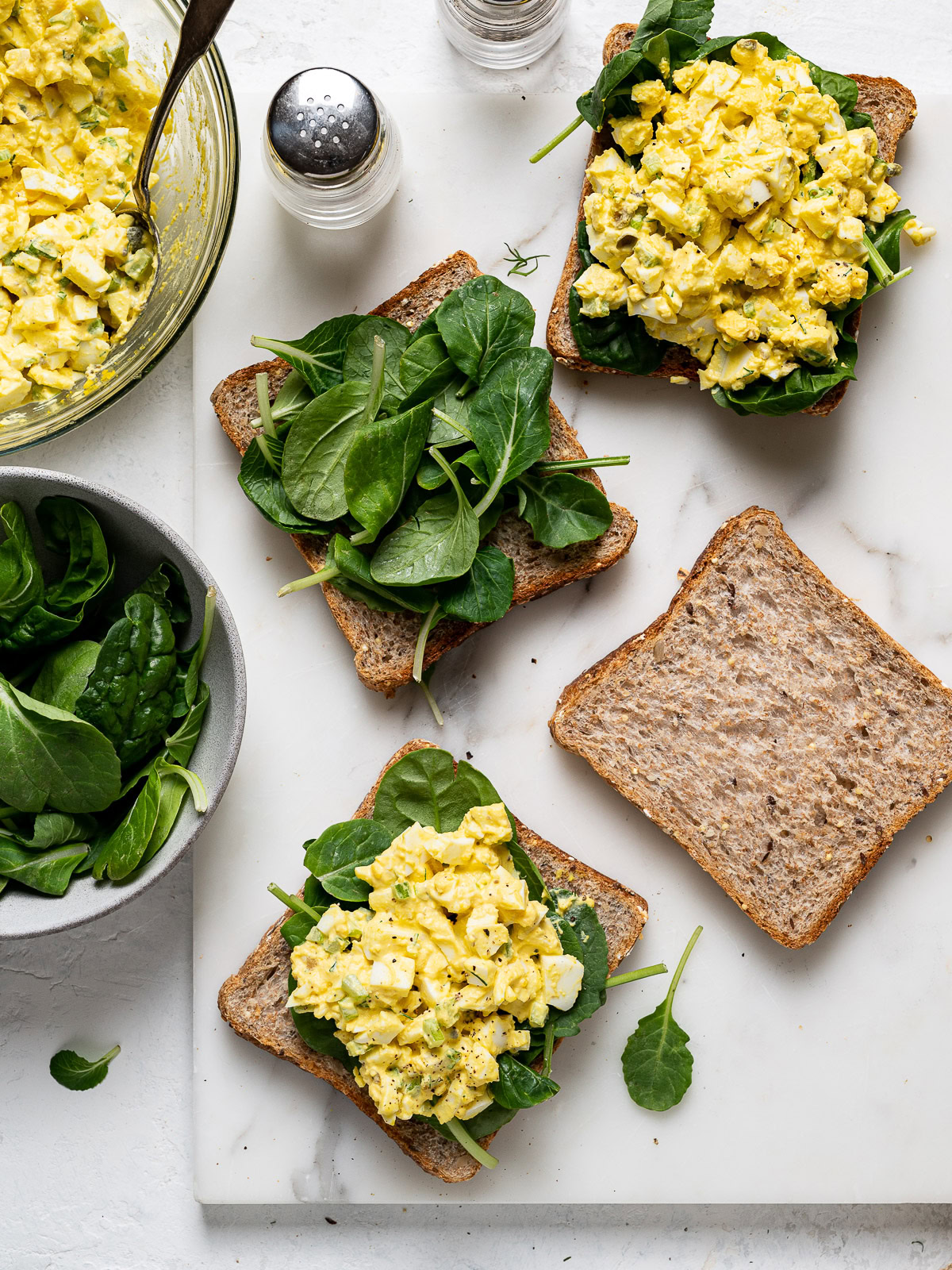 preparing egg salad sandwiches with leafy greens