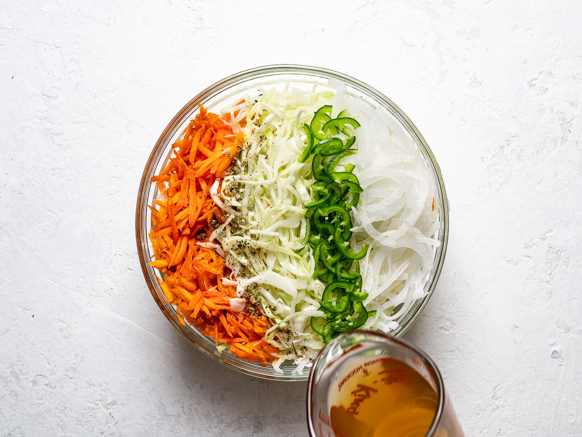 pouring vinegar over veggies in bowl 