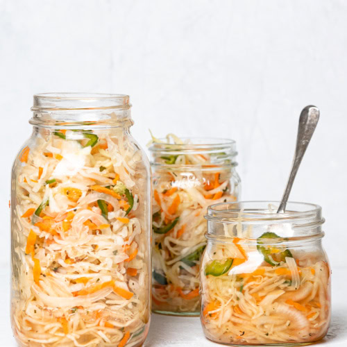 Three mason jars filled with curtido (Salvadoran slaw)