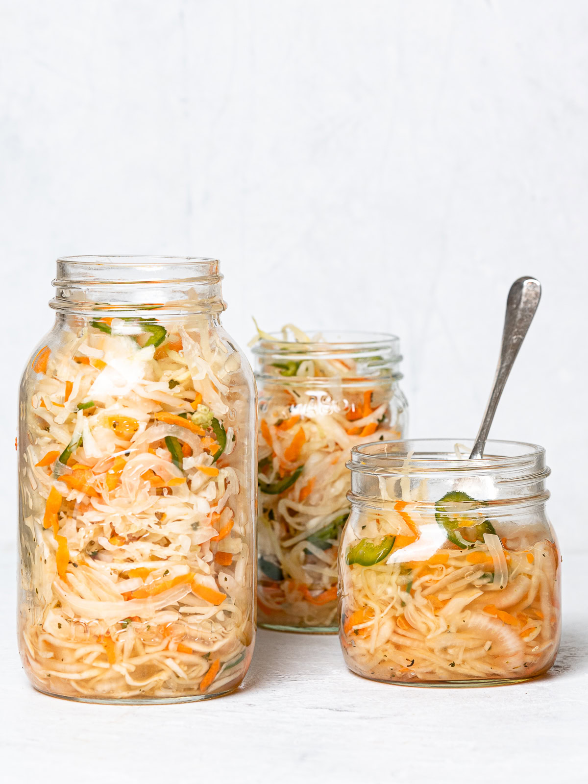 Three mason jars filled with curtido (Salvadoran slaw)