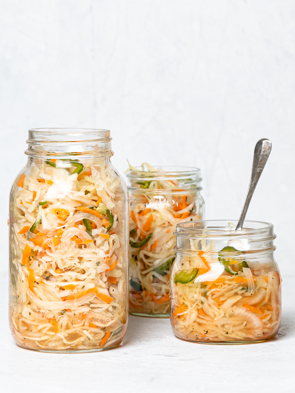 side view of Three mason jars filled with curtido (Salvadoran slaw)
