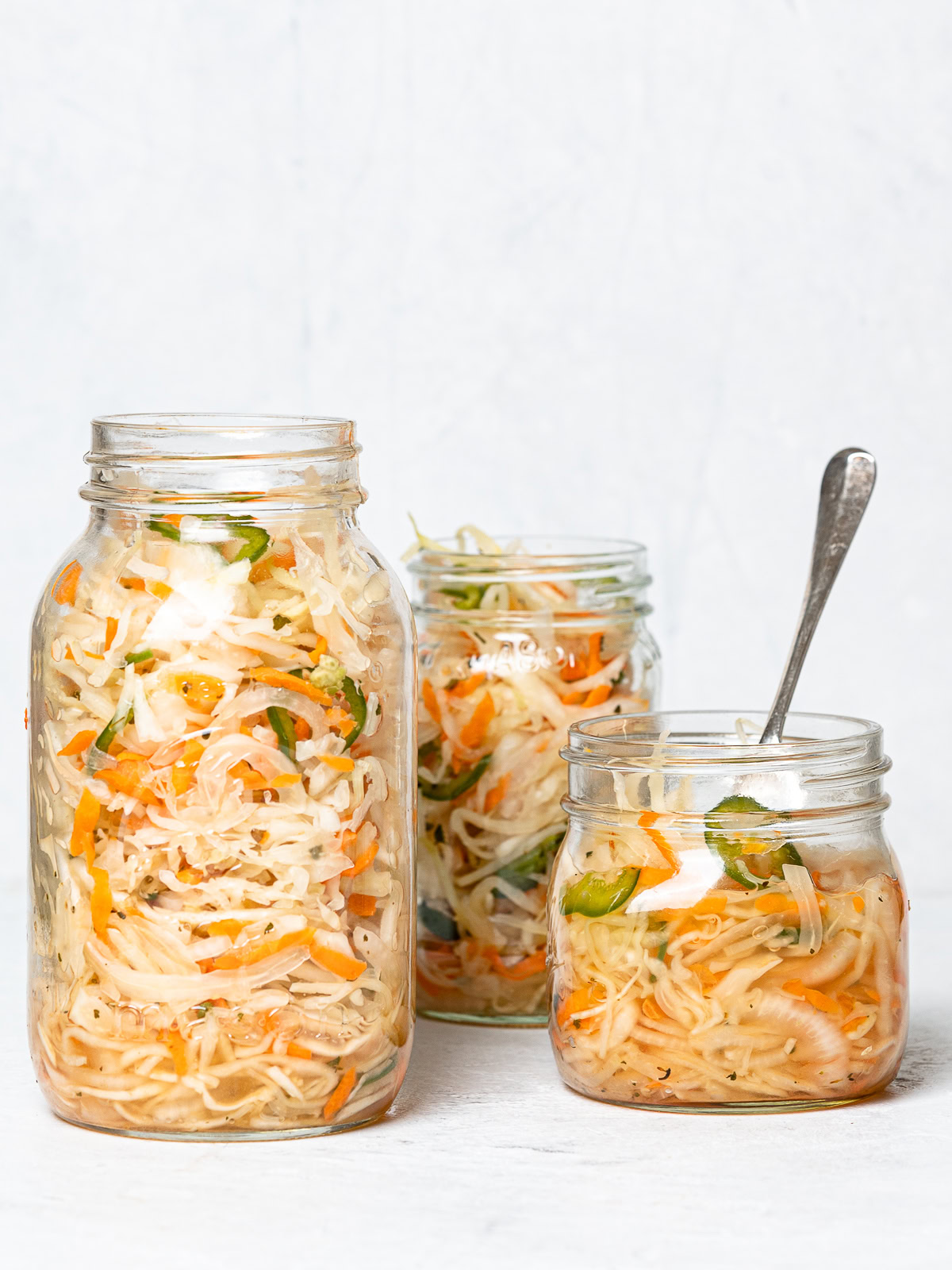 side view of Three mason jars filled with curtido (Salvadoran slaw)