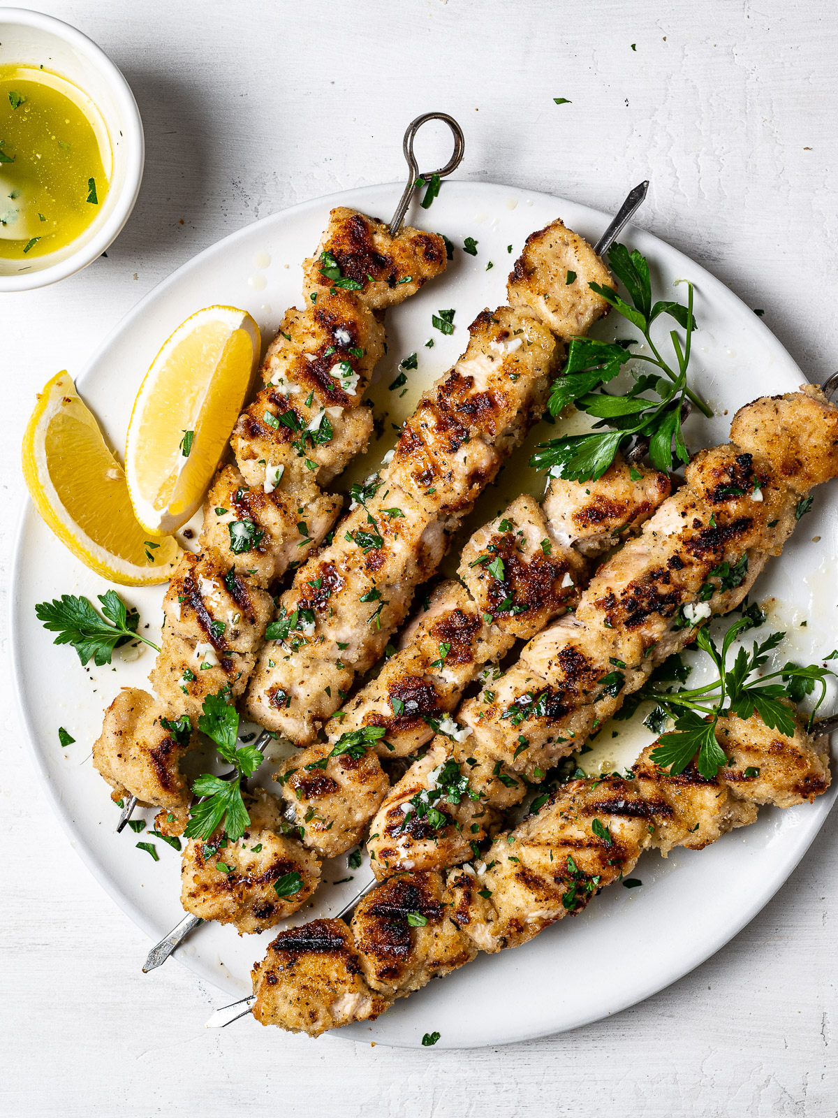 grilled chicken spiedini skewers served on platter with lemon wedges and lemon butter sauce on the side