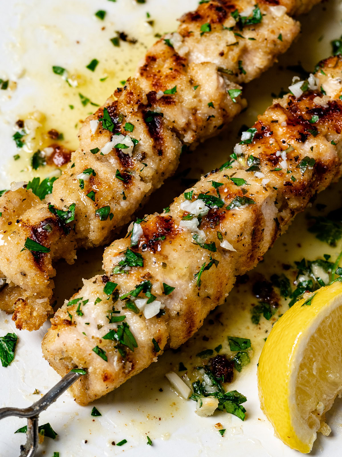 close-up of two grilled chicken spiedini skewers served on platter 