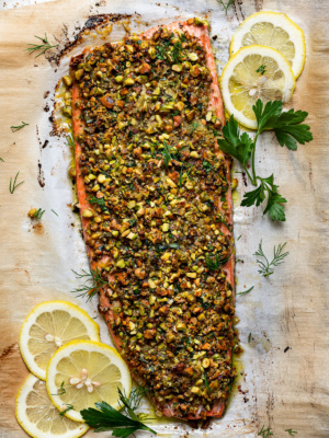 baked pistachio-crusted salmon on baking sheet garnished with dill and lemon slices