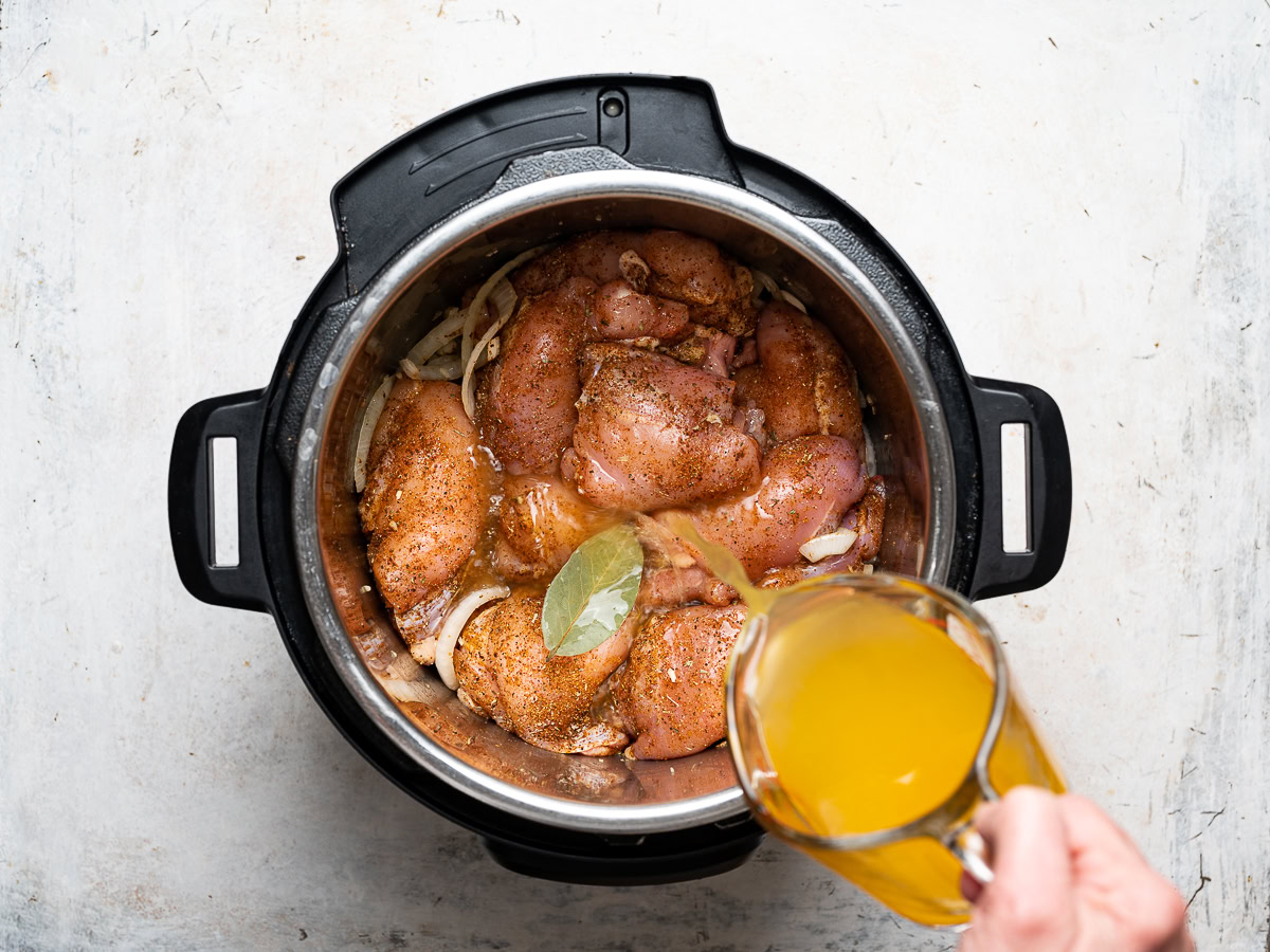 pouring citrus juice over uncooked chicken thighs in Instant pot