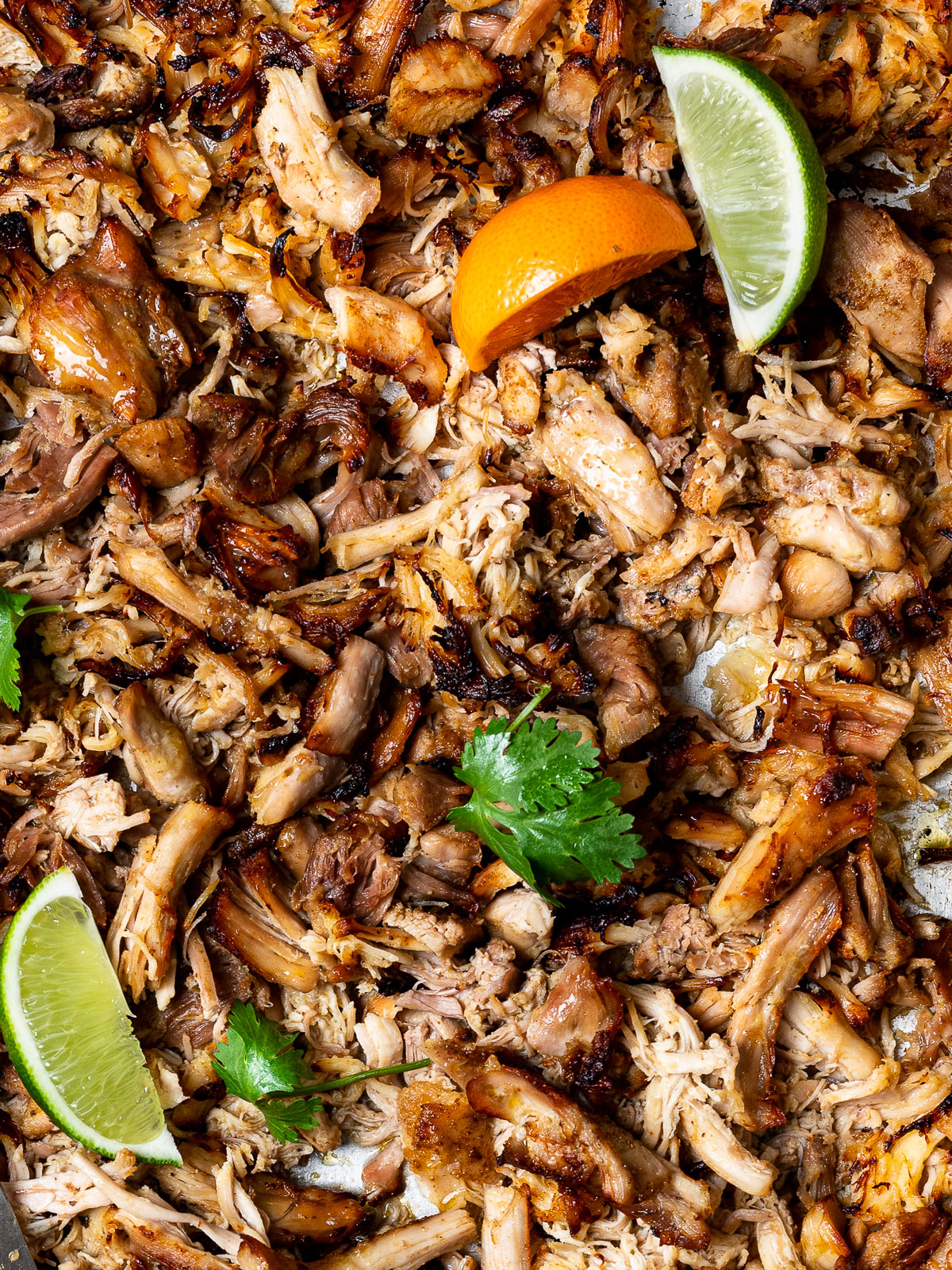 close-up of Crispy chicken carnitas on sheet pan with lemon wedges