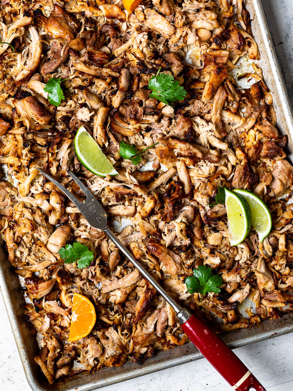 Crispy chicken carnitas on sheet pan with lemon wedges