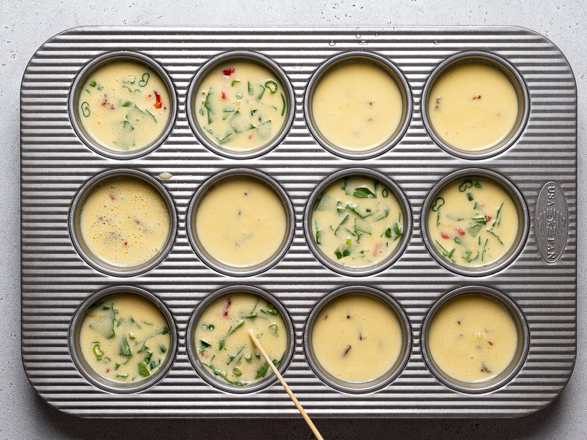 pre-baked egg bites in muffin topped with add-in ingredients pushed down into mixture