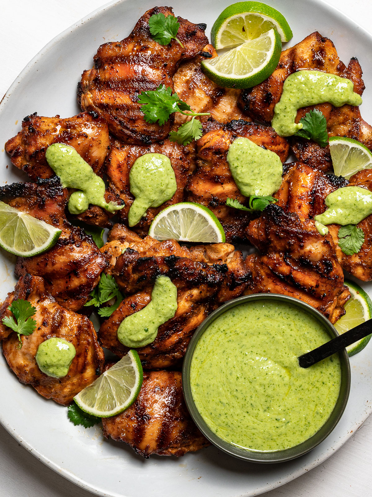 grilled chicken served on platter drizzled with green sauce