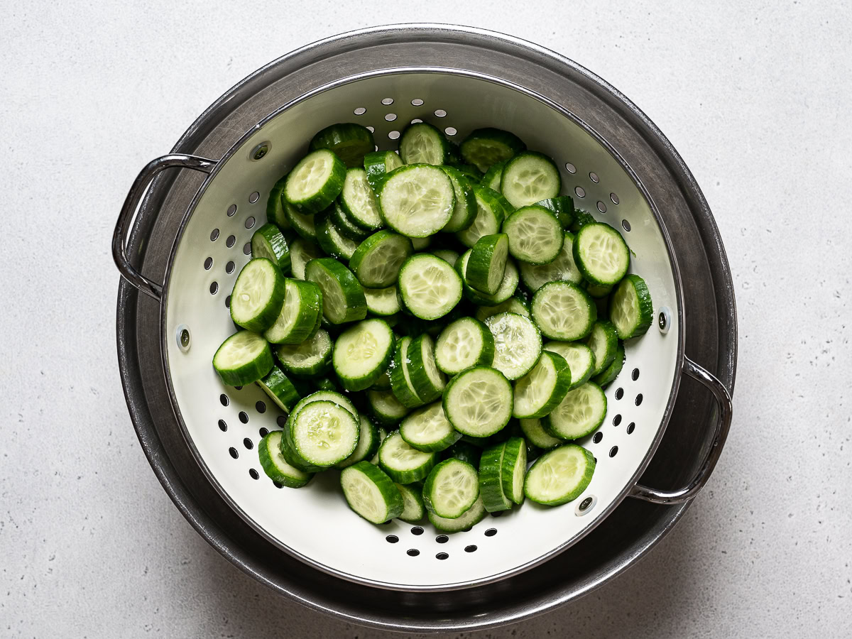 salted cucumbers draining in colander