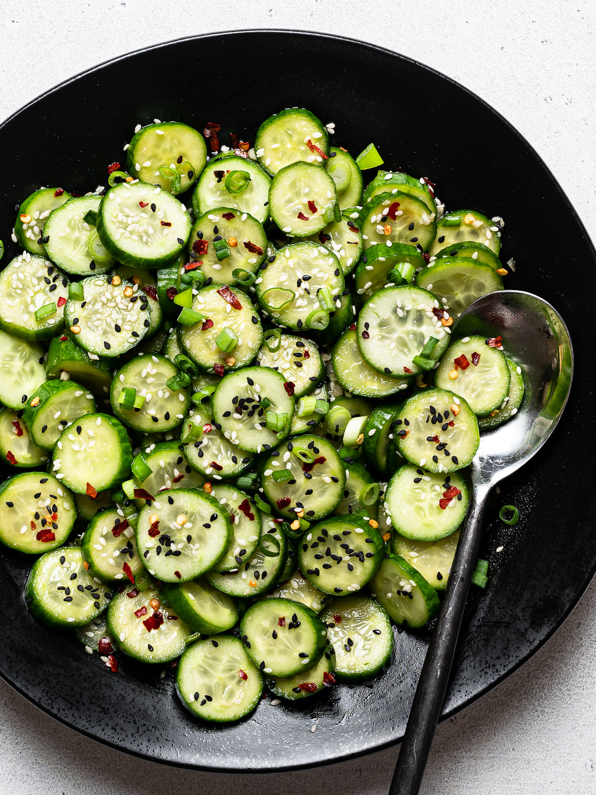 close up of Sesame cucumber salad served in black bowl