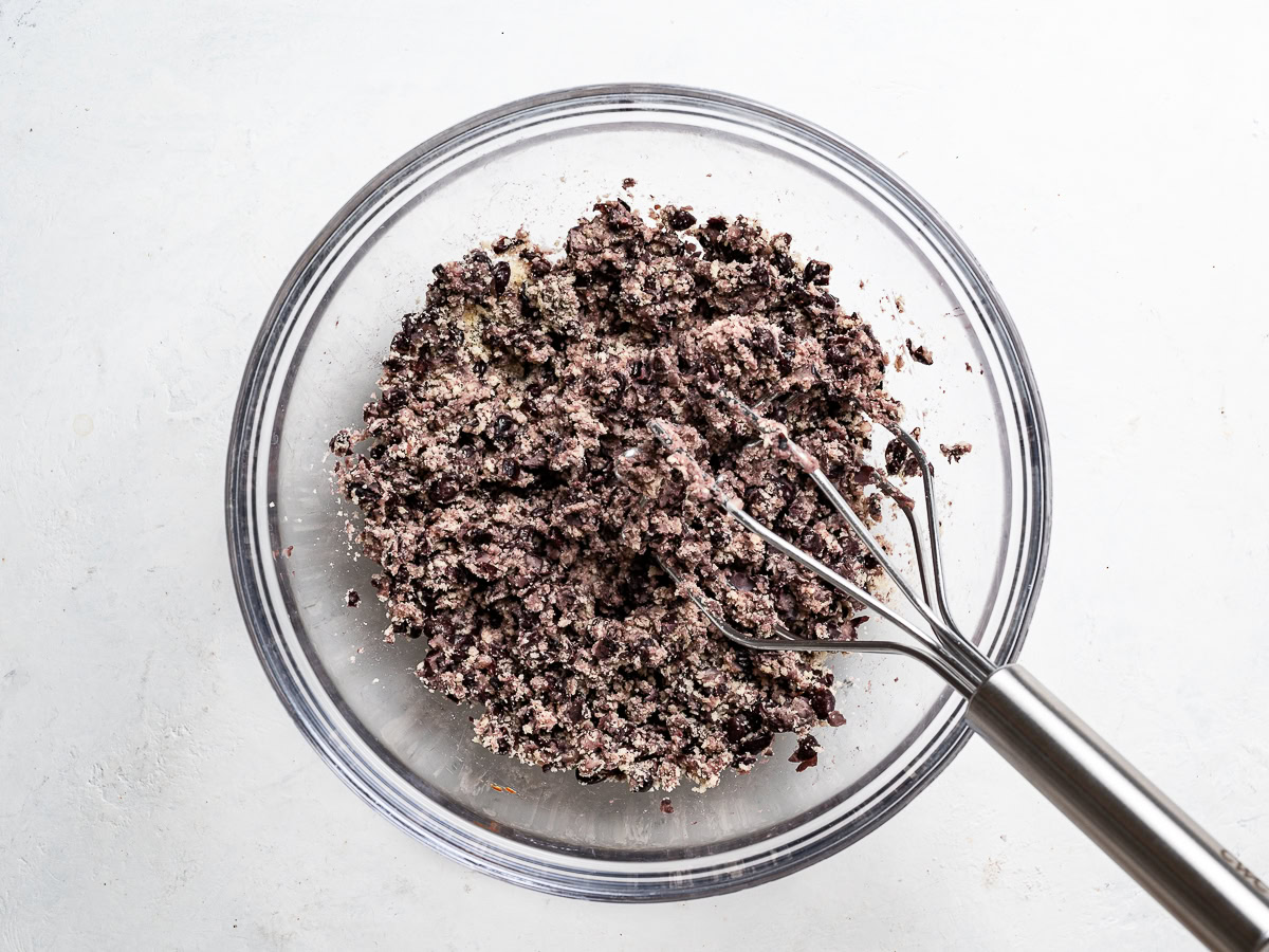 mashing beans in bowl with potato masher