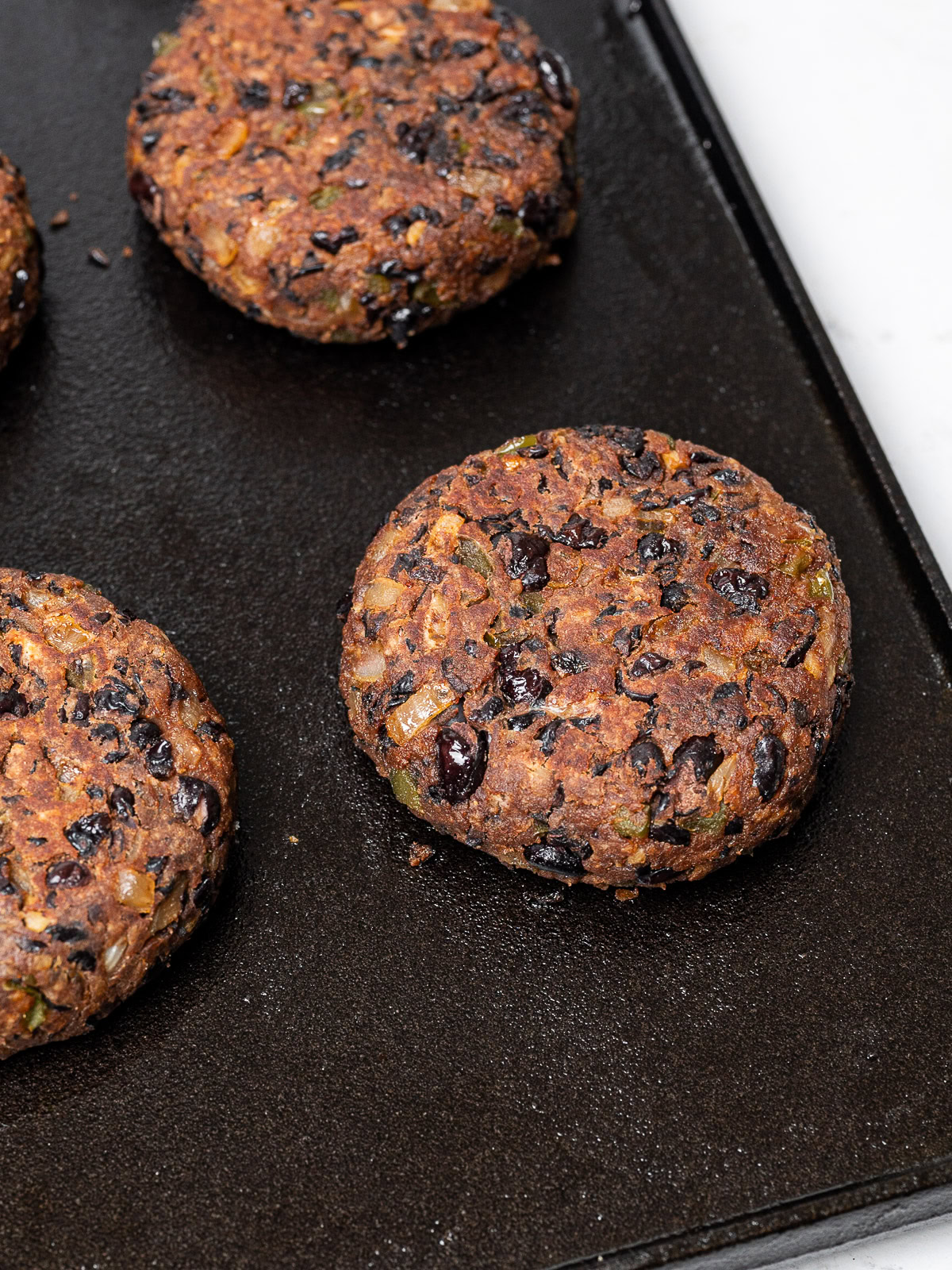 close up of cooked burgers on griddle pan