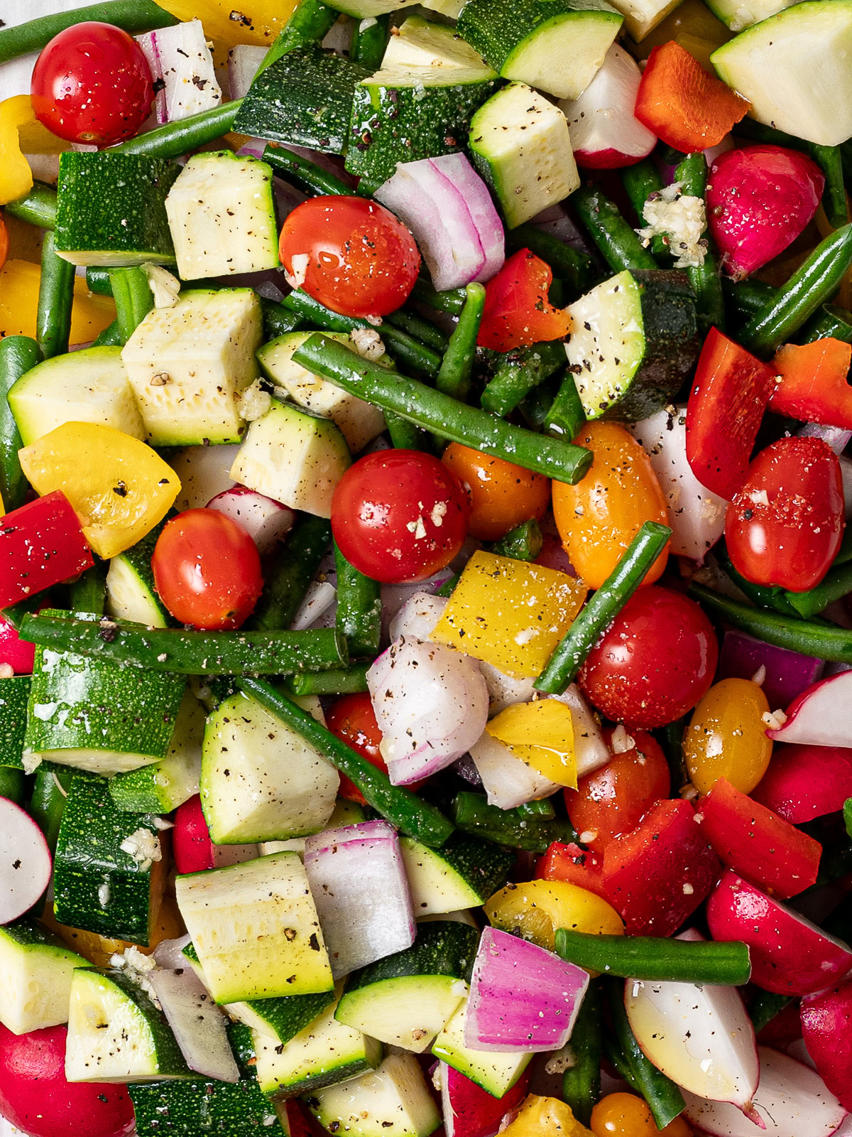 close up of raw chopped veggies piled onto one baking sheet