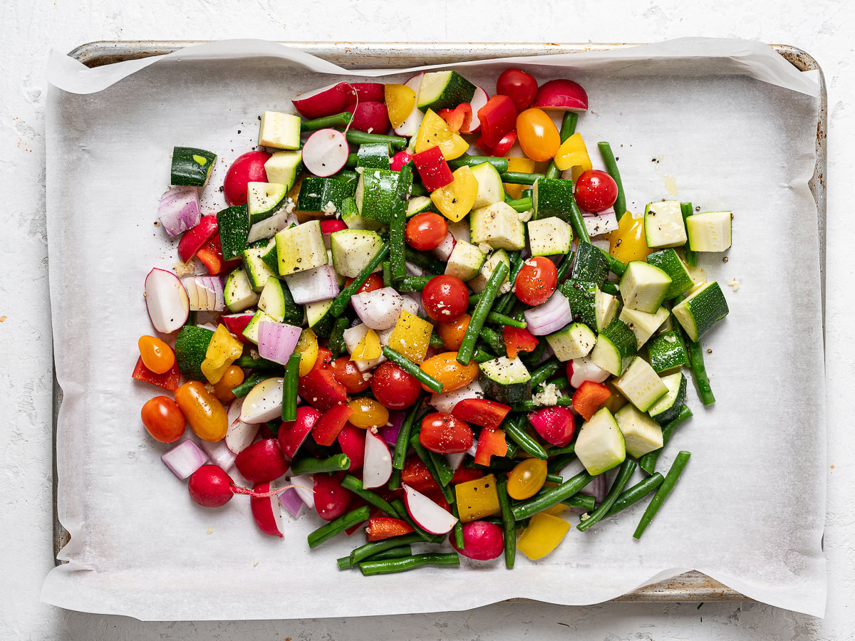 raw chopped veggies piled onto one baking sheet