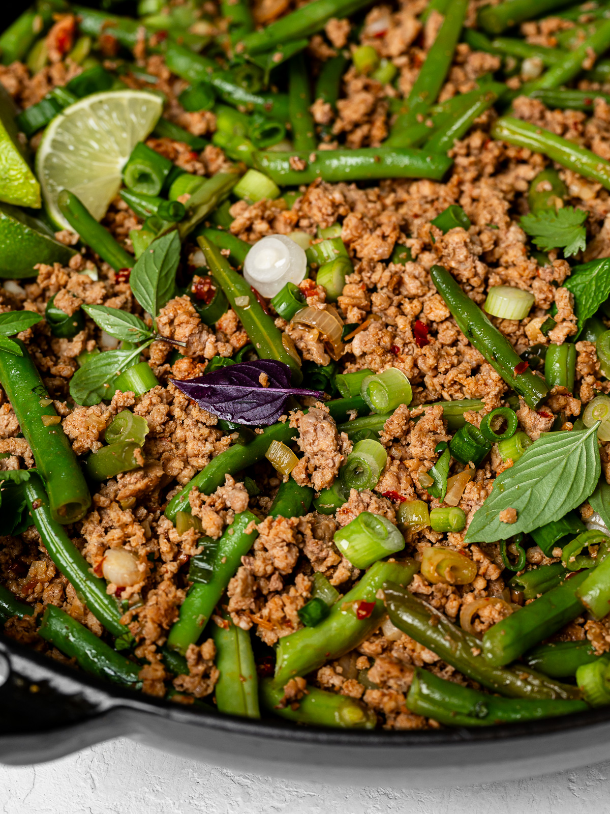 side-view close up of ground turkey and green bean mixture mixed in skillet garnished with herbs