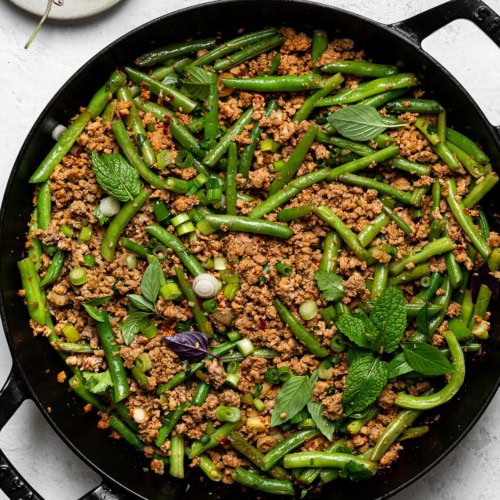 turkey and green bean stir-fry in skillet garnished with herbs