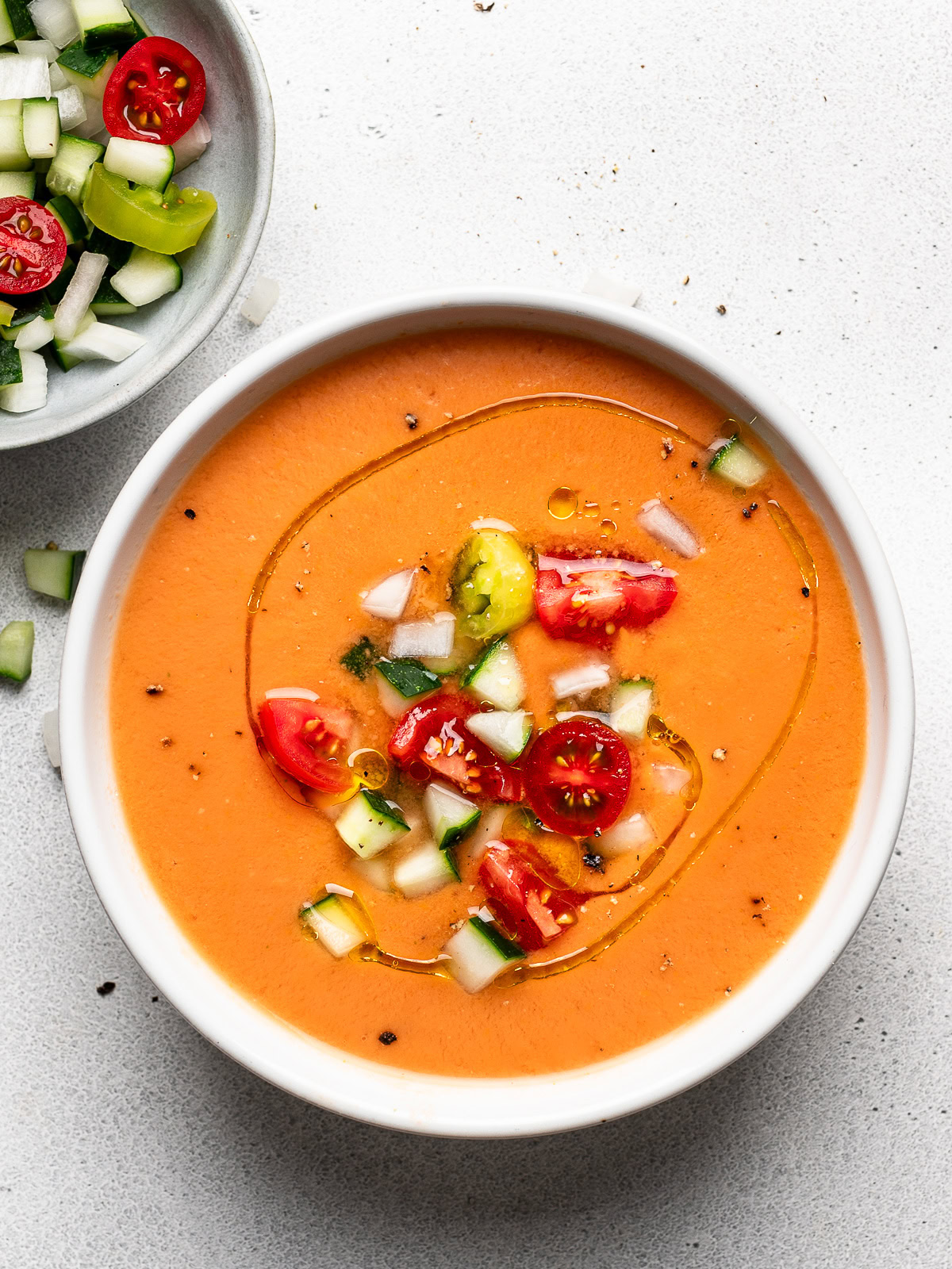 Gazpacho served in a white soup bowl topped with garnishes