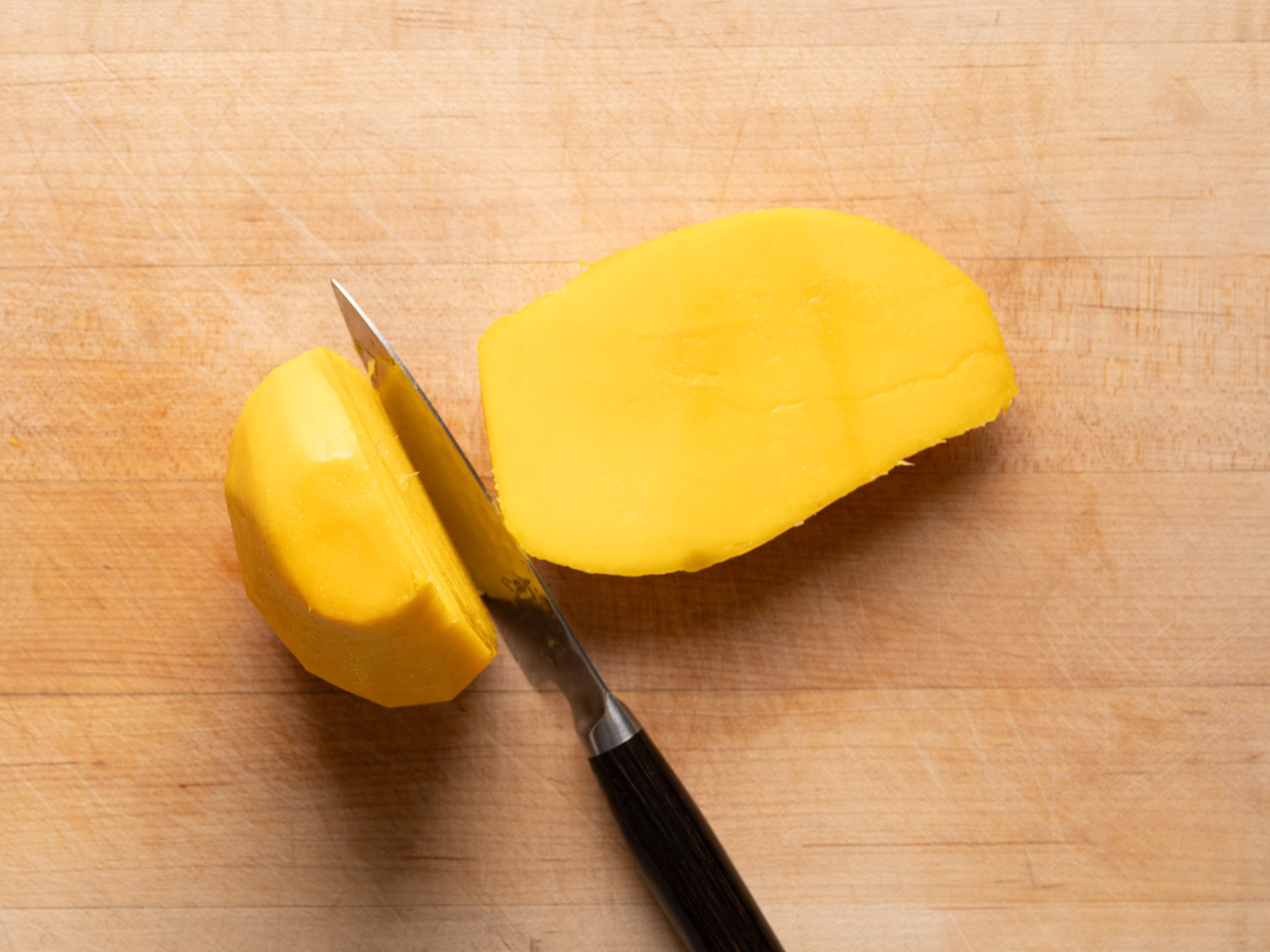 slicing a peeled mango on cutting board