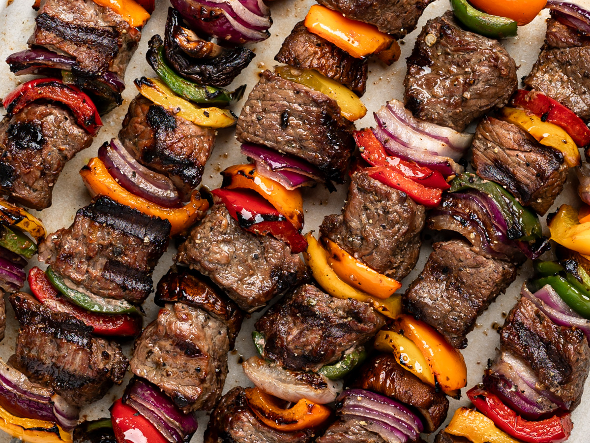 diagonal close up of grilled beef shish kebobs (cubes of beef on skewers with vegetables)