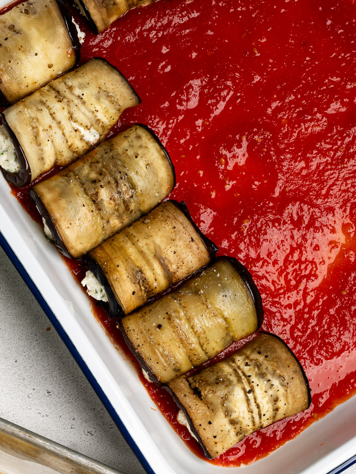 a few rolled eggplant bundles in casserole dish with tomato sauce