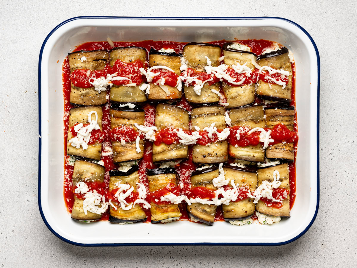 un-baked prepared rollatini bundles  in casserole dish topped with cheese 