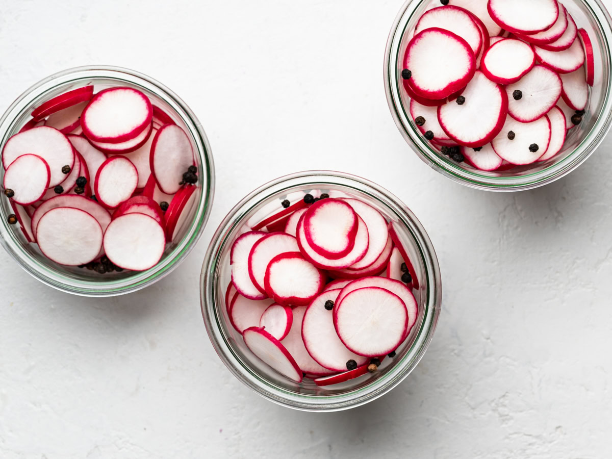 sliced radishes stuffed into 3 glass jars