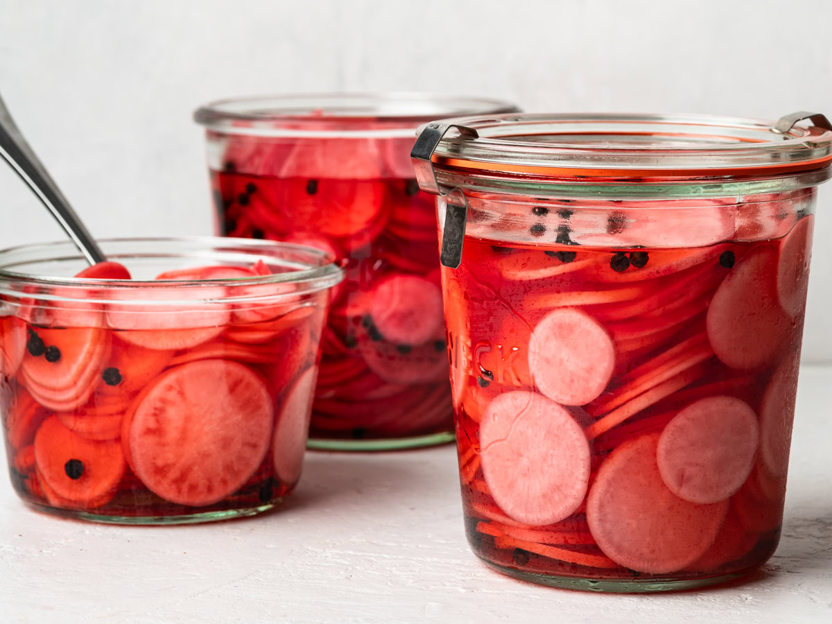 horizontal image of 3 jars filled with pickled radishes