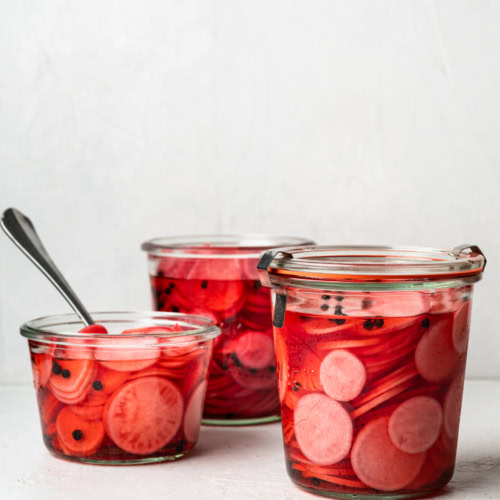 vertical image of 3 jars filled with pickled radishes