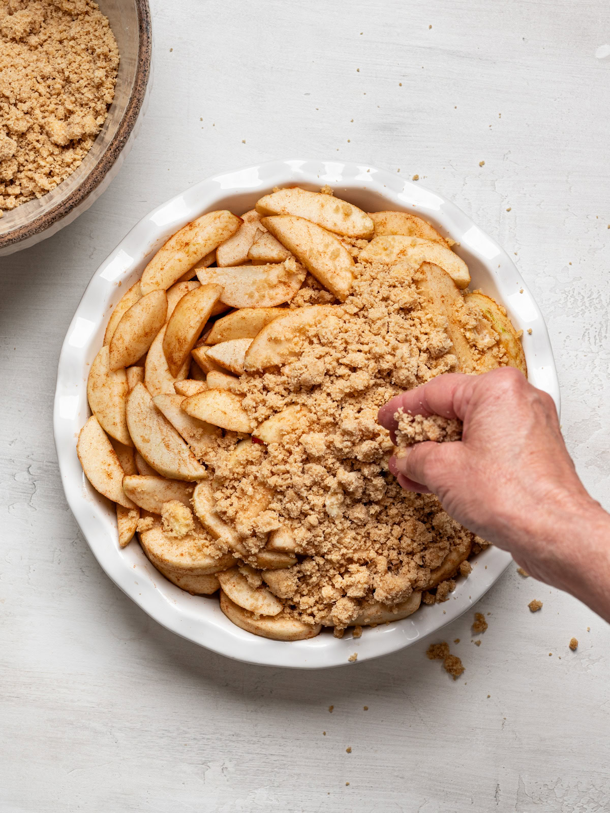 image of hand sprinkling topping over sliced apples