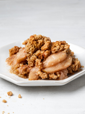 A side view of a serving of apple crisp without oats on a white plate