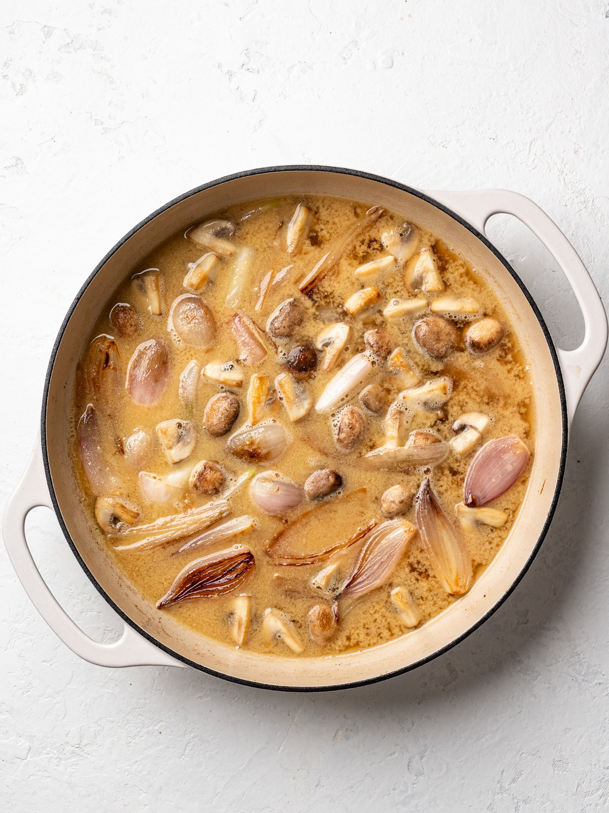 wine and mustard sauce cooking down in skillet with shallots and mushrooms