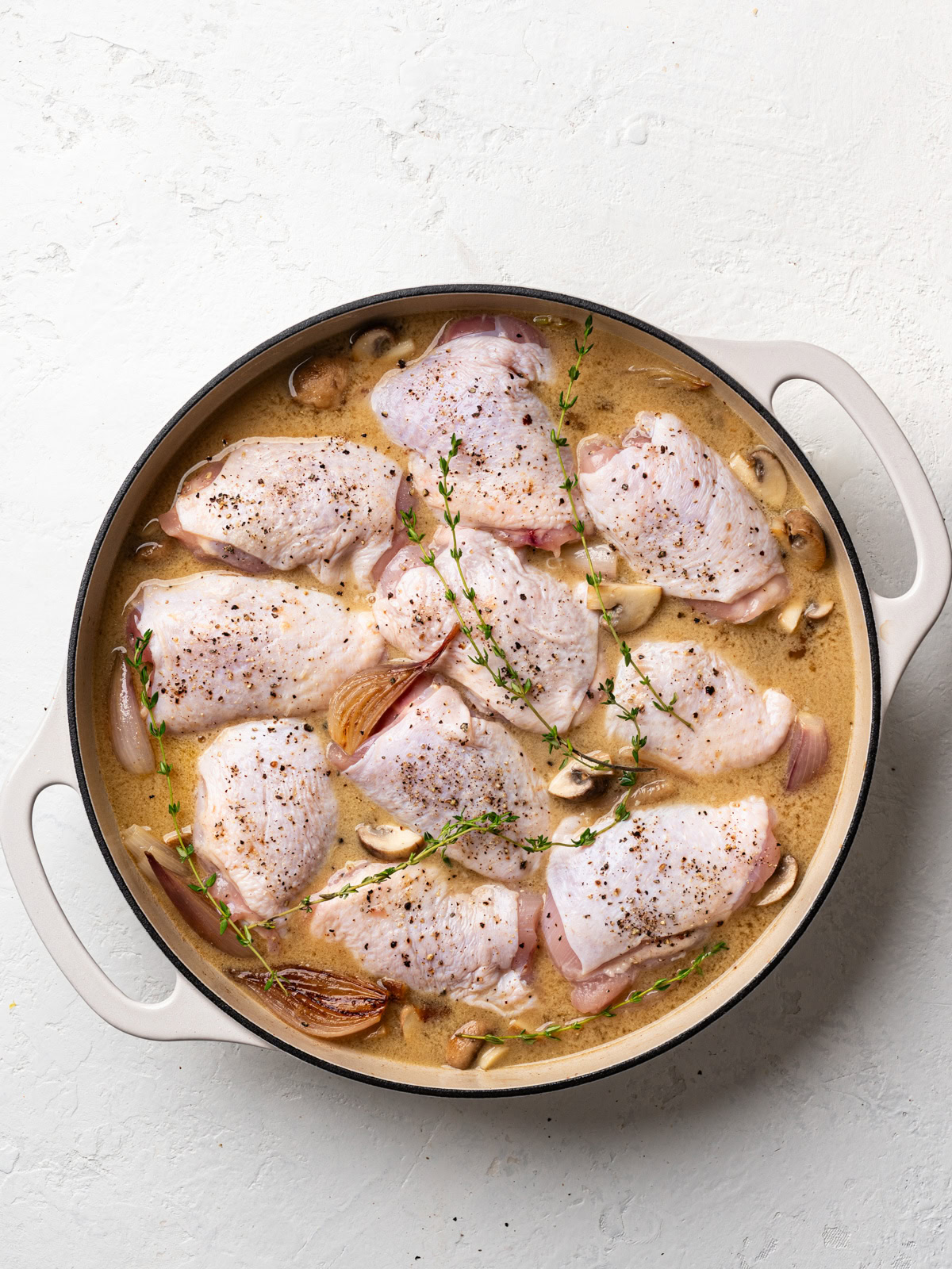 chicken thighs in skillet with wine sauce and shallot-mushroom mixture