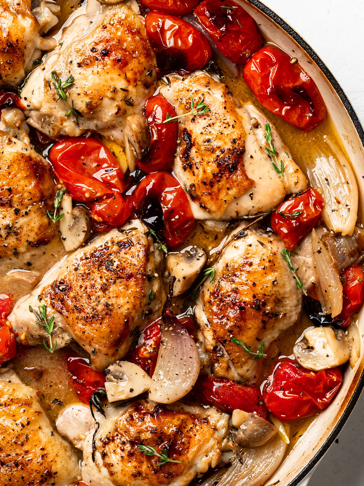 close up of finished dish of braised chicken with tomatoes and shallots in skillet.