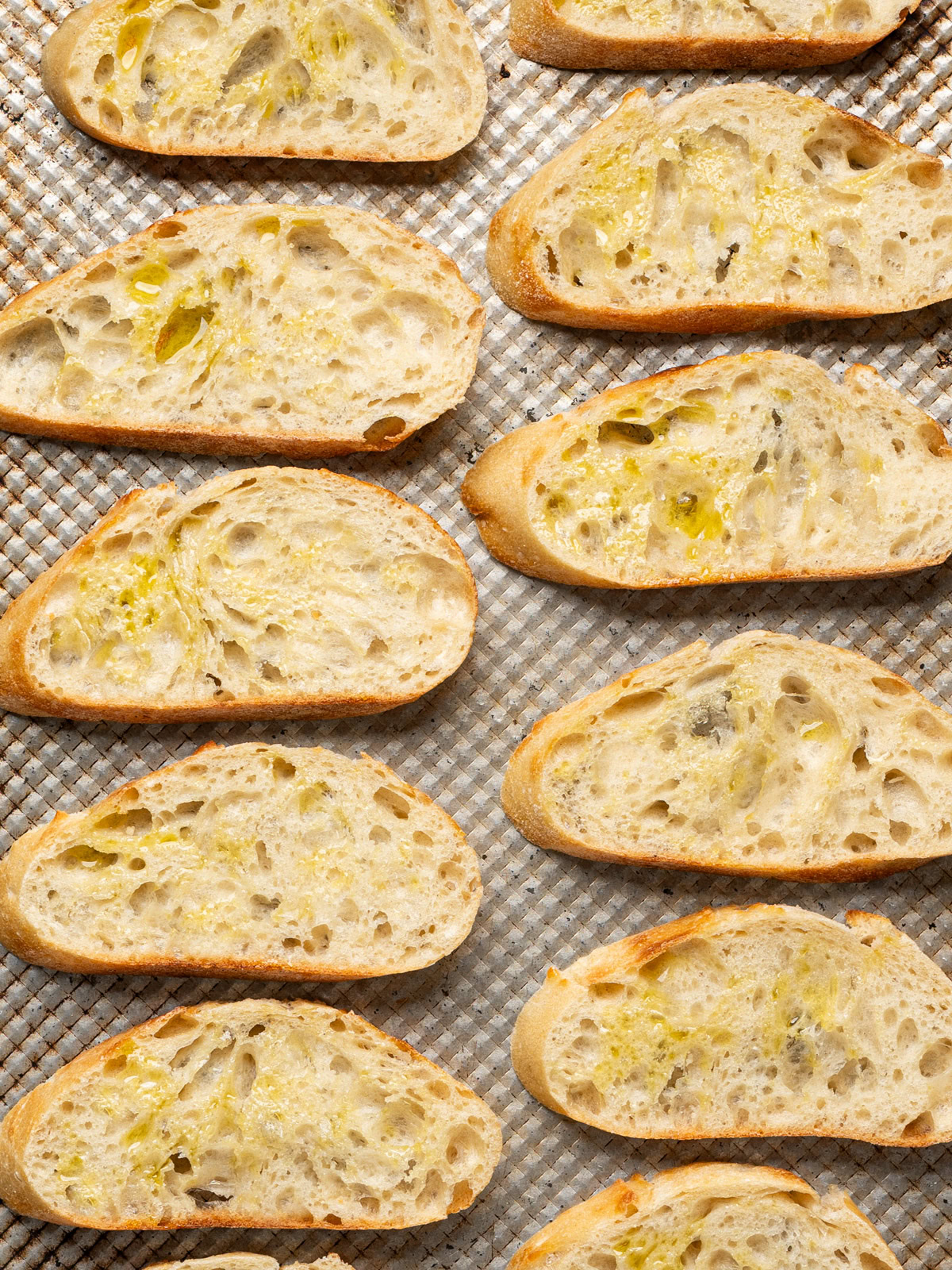 un-toasted bread slices drizzled with olive oil on baking sheet