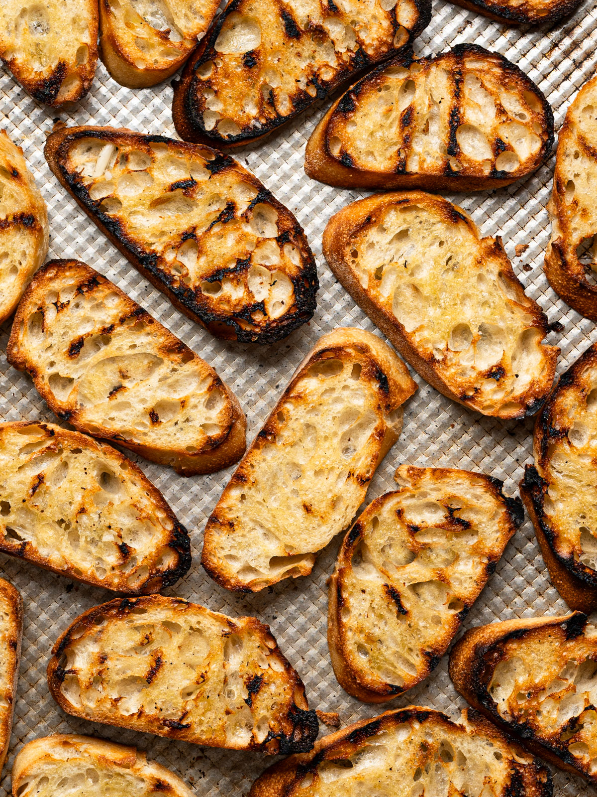grilled and toasted bread slices on baking sheet