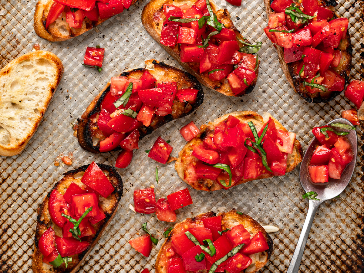 topping the toasted bread slices on a baking sheet with tomato mixture 