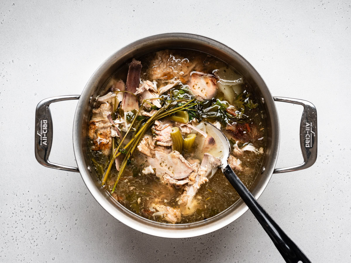 turkey stock in large soup pot with a lot of turkey bones and some herbs