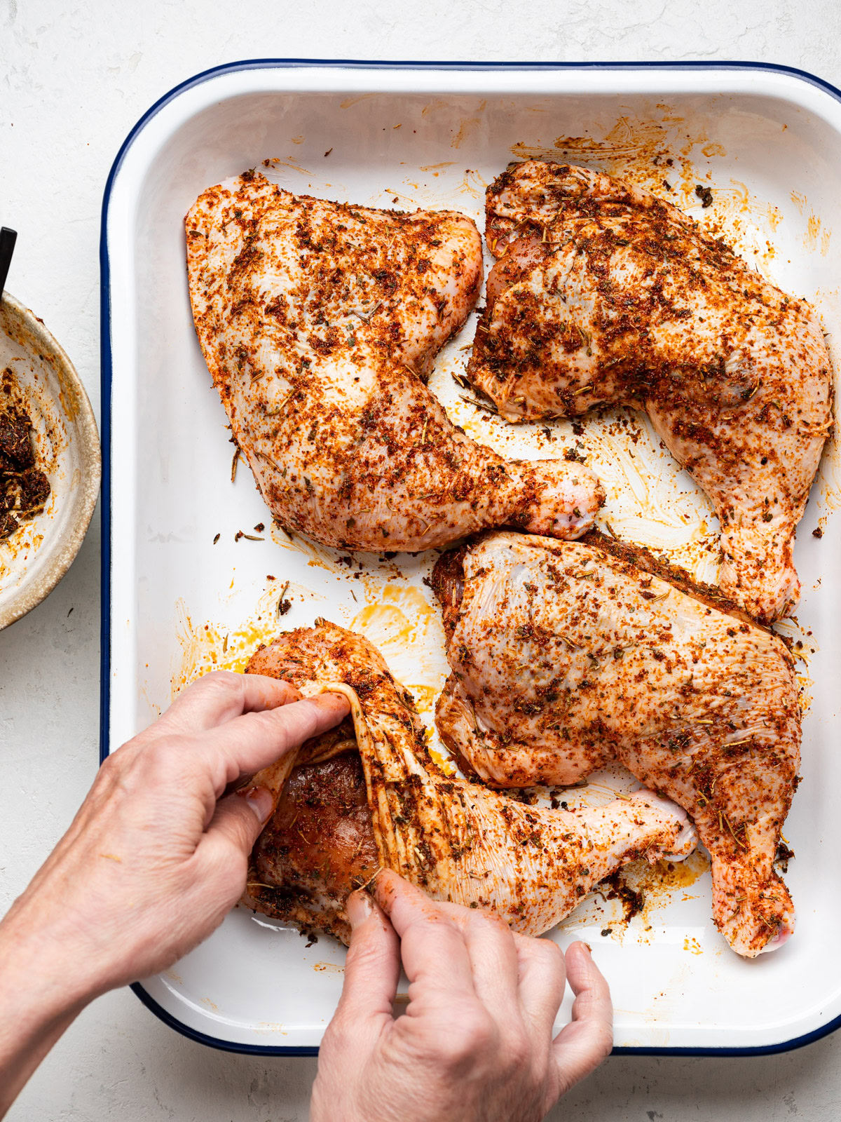 rubbing spice mixture under the skin of a chicken leg quarter