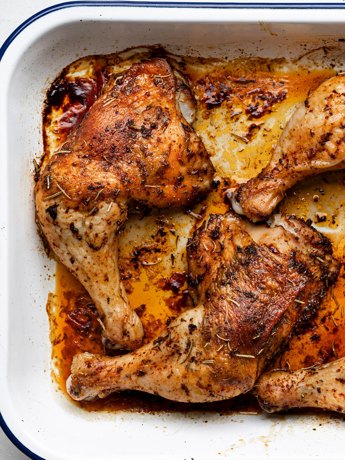 close up of baked chicken leg quarters in baking dish