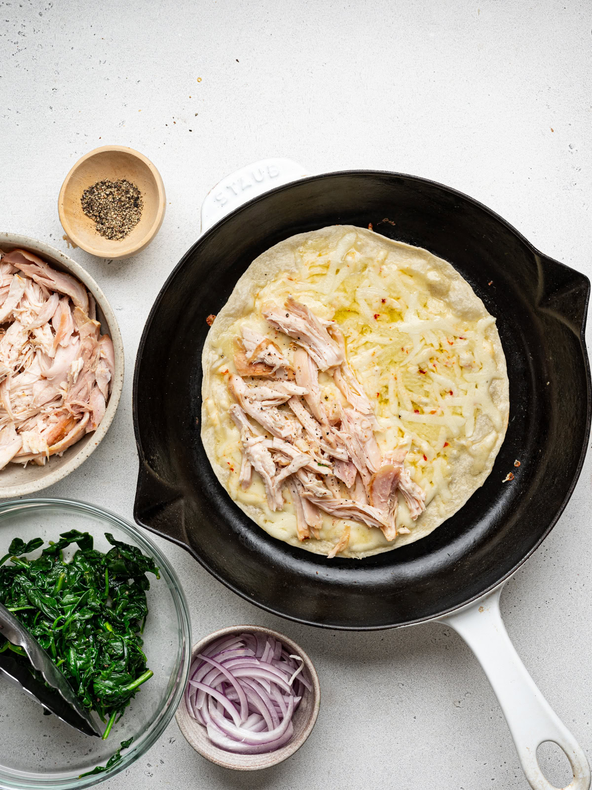 wilted spinach and red onion slices layered over shredded chicken