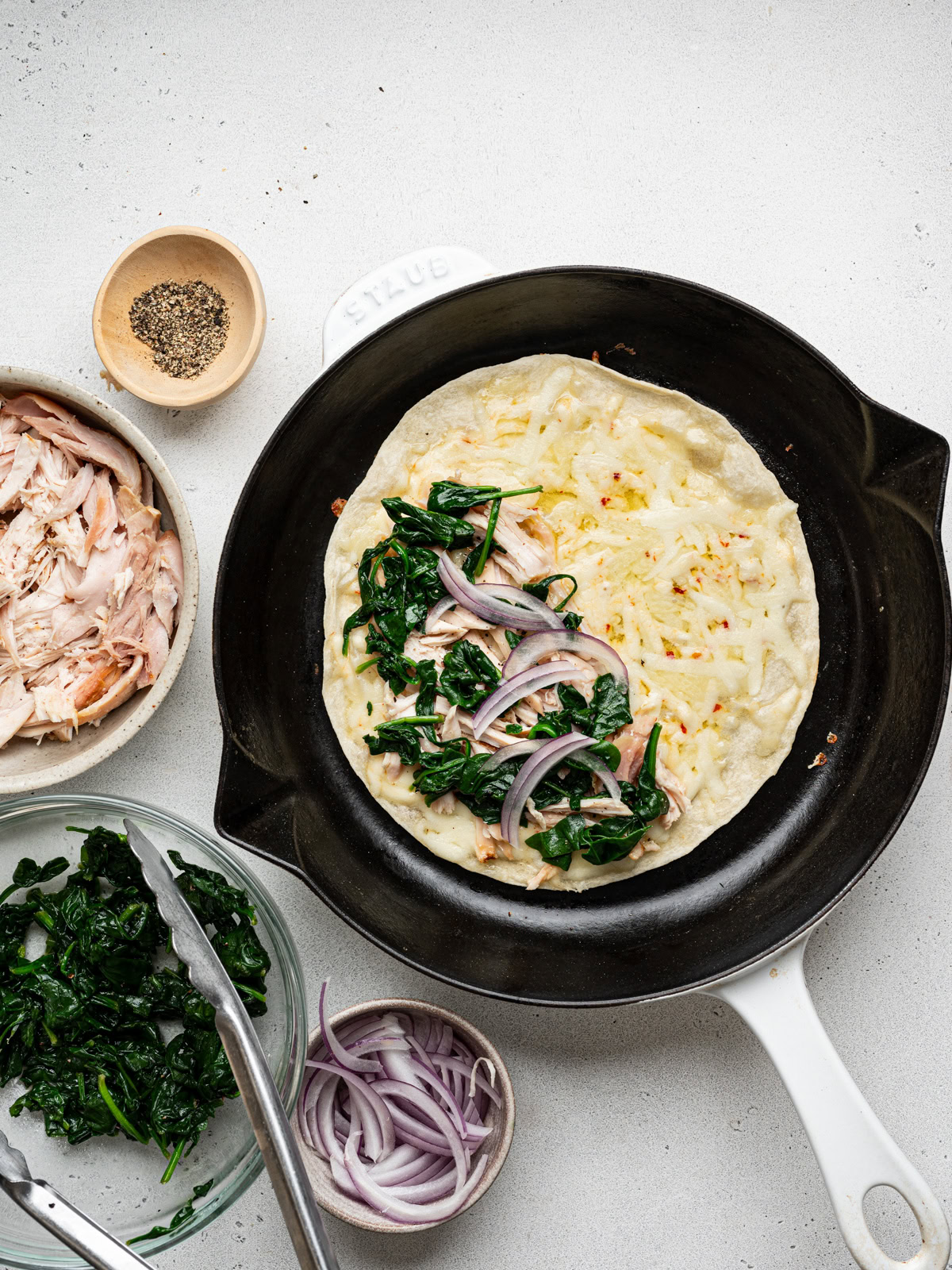 wilted spinach and red onion slices layered over shredded chicken