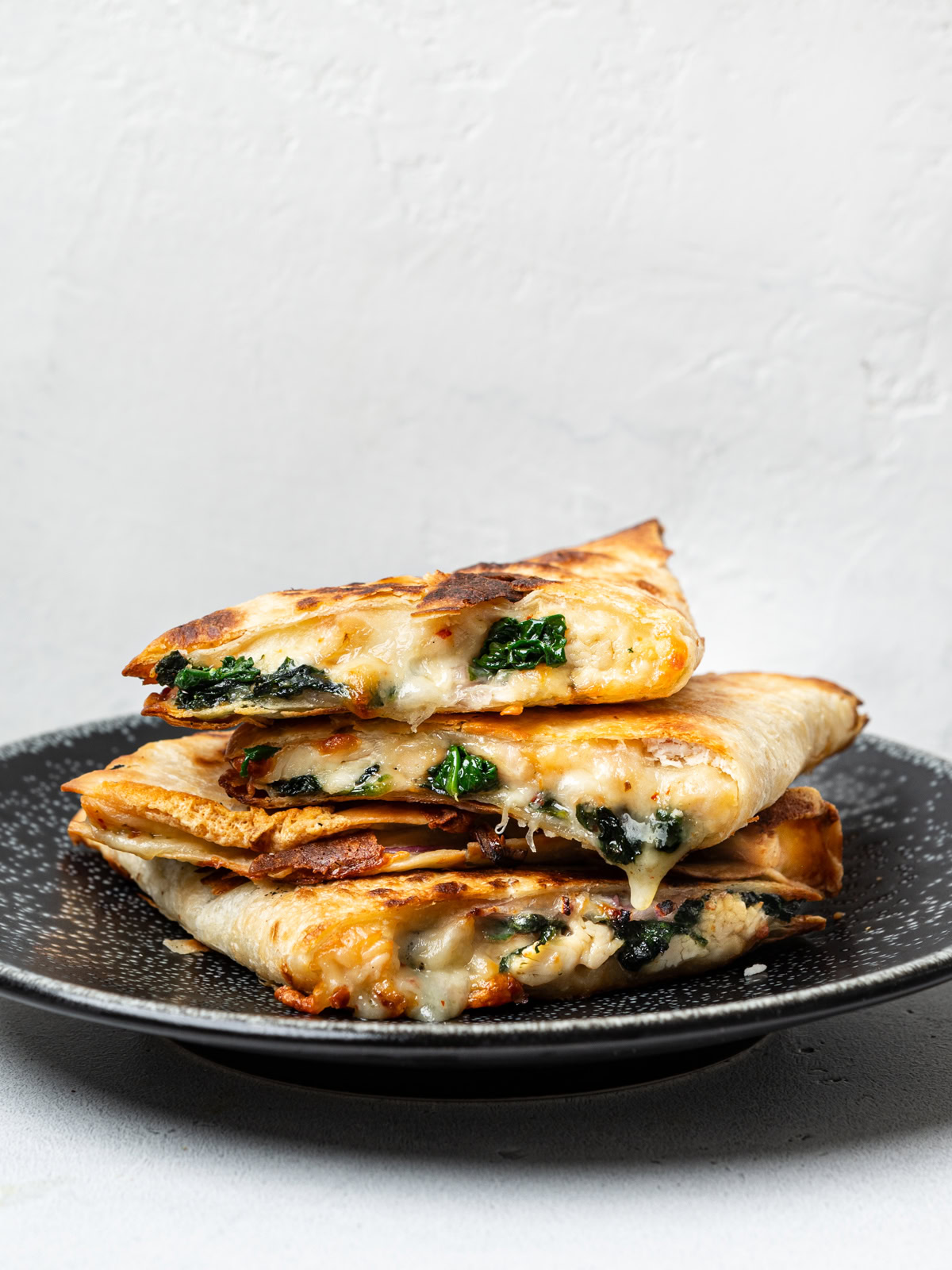 side view of a stack of 4 quesadillas on a black plate