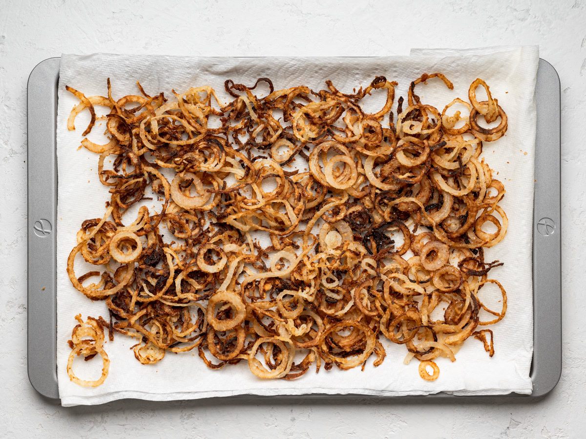 fried crispy onions on paper towel-lined sheet pan