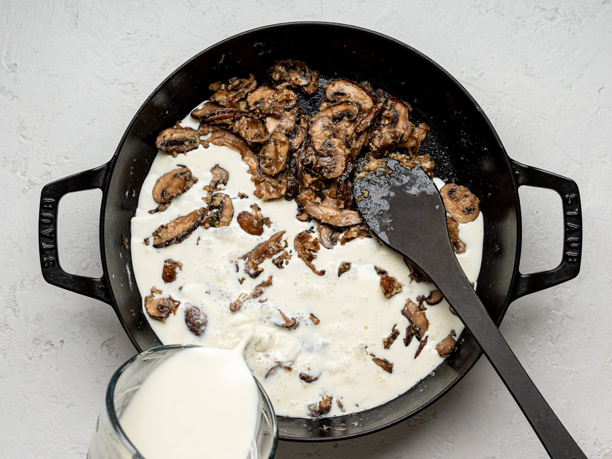 pouring milk into skillet with browned mushroom mixture