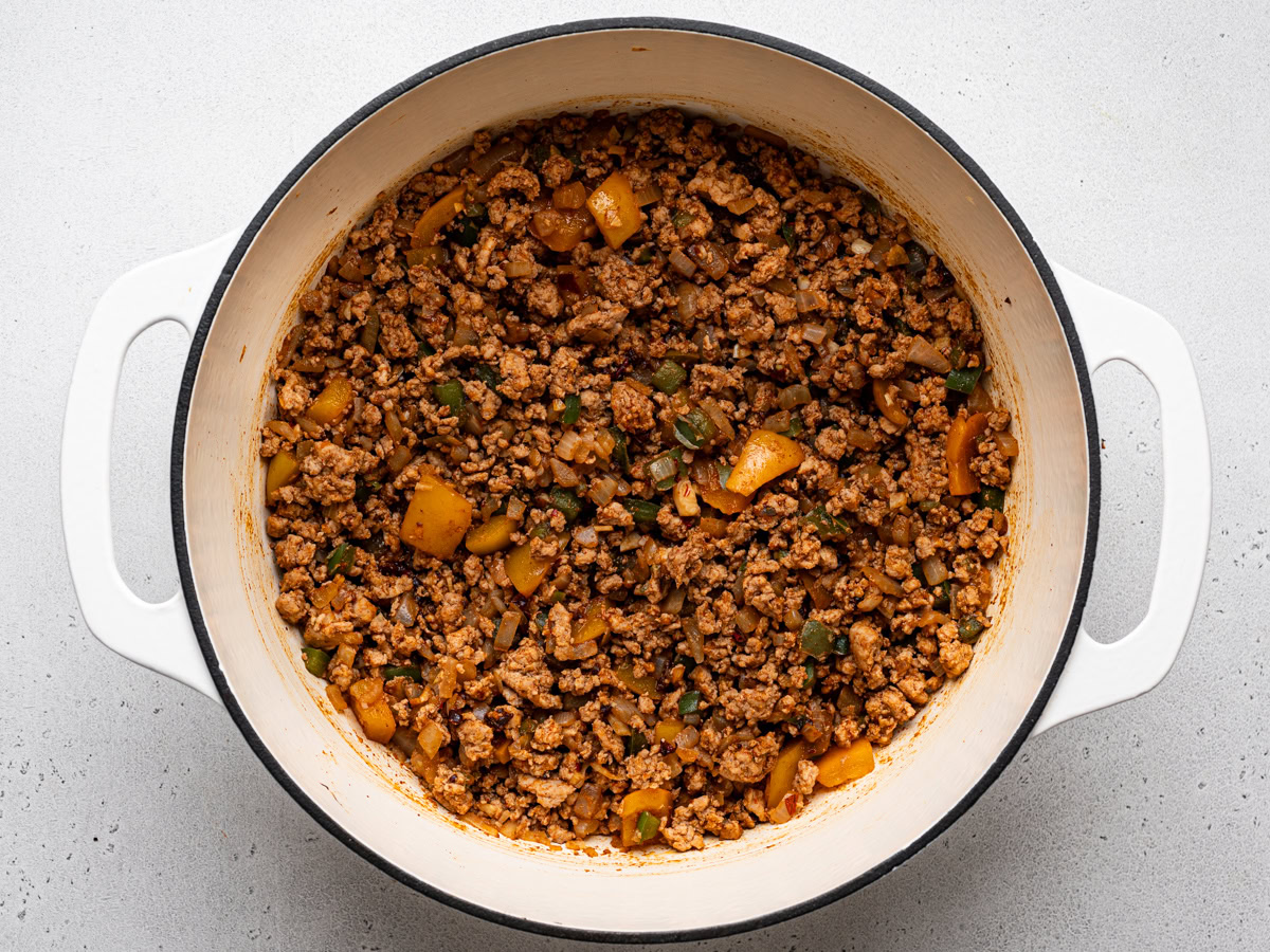 turkey mixture in pot with the addition of tomato sauce and spices